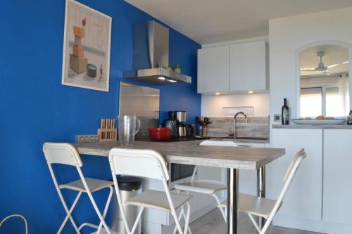 une cuisine avec des murs bleus et un comptoir avec des chaises blanches dans l'établissement Appart 2 pièces 4 couchages BANYULS SUR MER BN120-4217, à Banyuls-sur-Mer