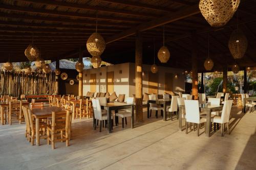 a restaurant with wooden tables and chairs and chandeliers at El Refugio de Vichayito in Vichayito