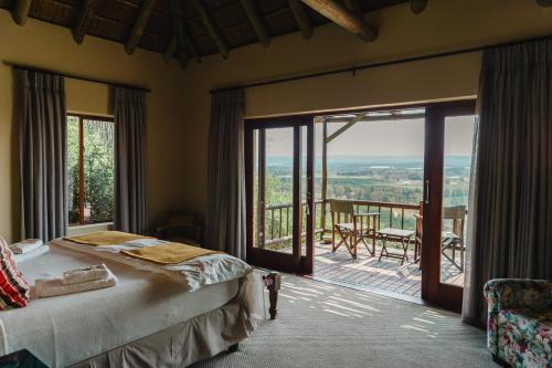 a bedroom with a bed and a balcony with a view at Hitgeheim Country Lodge in Addo