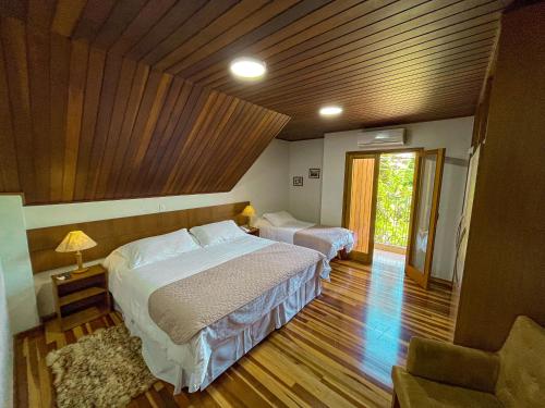 a bedroom with two beds and a wooden ceiling at Pousada Victoria Villa By Nacional Inn - A 800 metros da Vila Capivari in Campos do Jordão