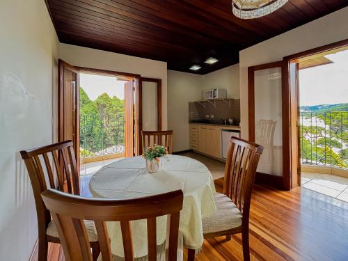 a dining room with a table and chairs and a kitchen at Pousada Victoria Villa By Nacional Inn - A 800 metros da Vila Capivari in Campos do Jordão