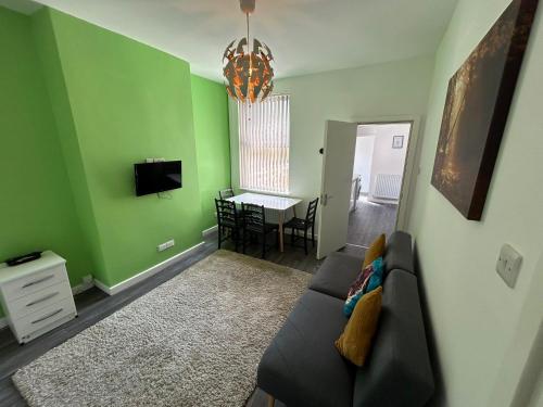 a living room with green walls and a couch at 4 Bed Spacious Home - Perfect For Families & Contractors in Stoke on Trent