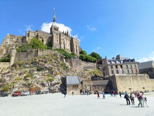 un groupe de personnes debout sur une plage en face d'un château dans l'établissement La Mont Doloise, à Mont-Dol