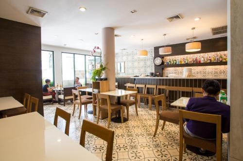 a restaurant with tables and people sitting at tables at Aphrodite Inn Bangkok in Bangkok