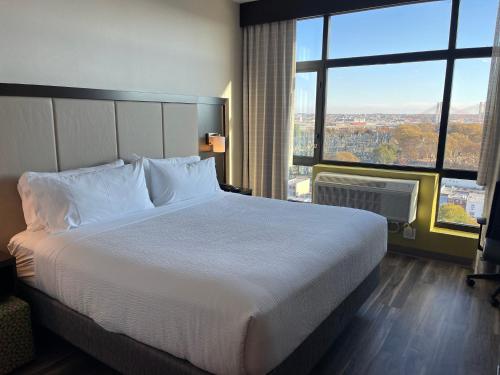 a large bed in a hotel room with a large window at Holiday Inn Express Long Island City E - New York by IHG in Queens