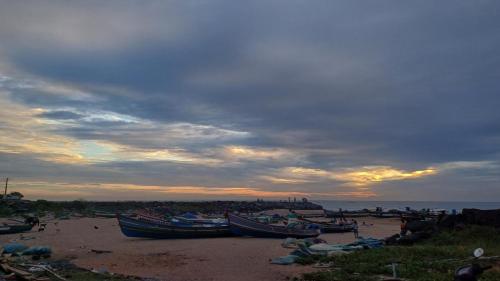 a group of boats sitting on the beach at sunset at DIVINE BEACH INN - The sea shore hotel in Puducherry