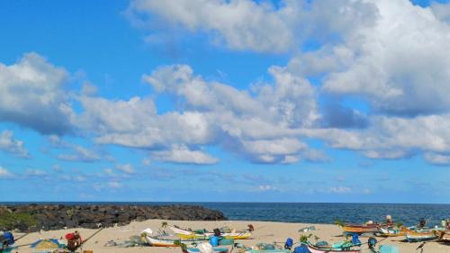 a group of people on a beach with a cloudy sky at DIVINE BEACH INN - The sea shore hotel in Puducherry
