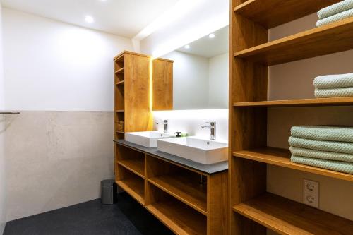 a bathroom with a white sink and wooden shelves at Lenzlhof in Mariapfarr