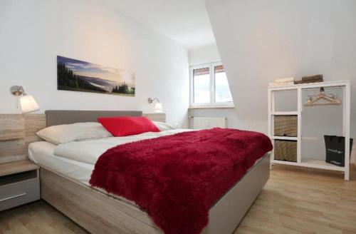 a bedroom with a bed with a red blanket on it at Ferienwohnung Holzer am Titisee in Titisee-Neustadt