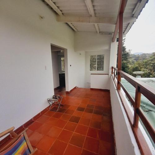 a balcony of a house with a red tile floor at Casa Campestre Encanto Rural in Anolaima