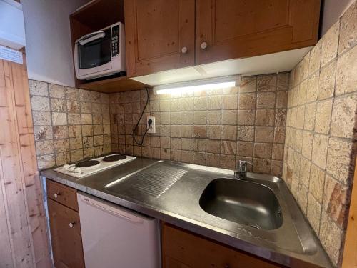 une cuisine avec un évier et un micro-ondes dans l'établissement Aiguille Verte 27 - Studio avec vue, à La Clusaz