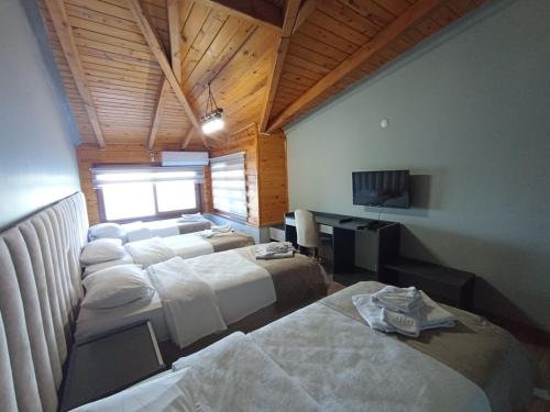 a hotel room with three beds and a television at Liman Butik Otel in Pazar