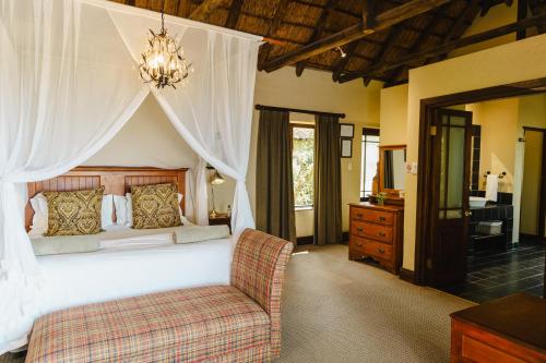 a bedroom with a large bed with a chandelier at Hitgeheim Country Lodge in Addo