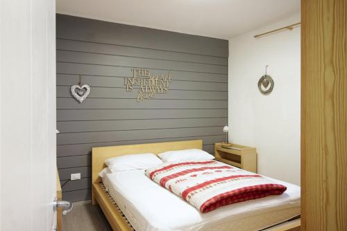 a bedroom with a bed with a gray wall at CASA 4 PIOPPI - Agenzia Dolomiti Affitti in Cavalese