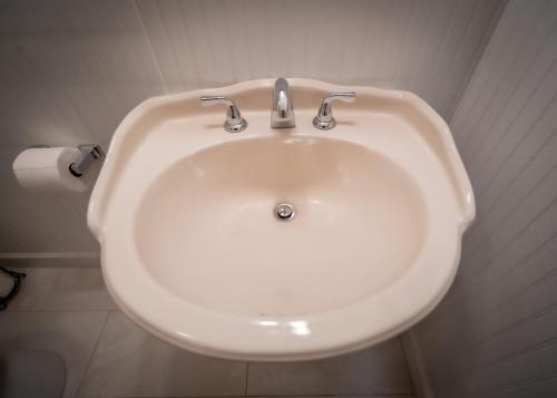 a white sink in a bathroom with a roll of toilet paper at Amazing House Hot Tub Mins To Major Hospitals in Middle Valley
