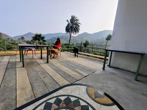 a woman sitting on a table with two dogs at 2BHK Cliff Side Villa in Mount Ābu