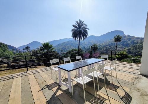 a table and chairs on a deck with a view of mountains at 2BHK Cliff Side Villa in Mount Ābu