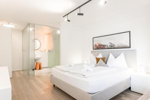 a white bedroom with a large bed and a bathroom at Lebe`schlitters - Das Ferienapartmenthaus im Zillertal in Schlitters