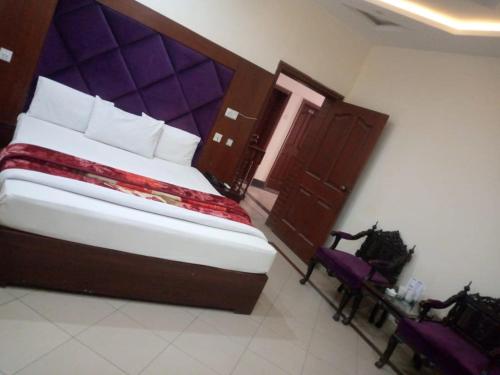 a bedroom with a large bed with a purple headboard at Hotel PAK Continentall Multan in Multan
