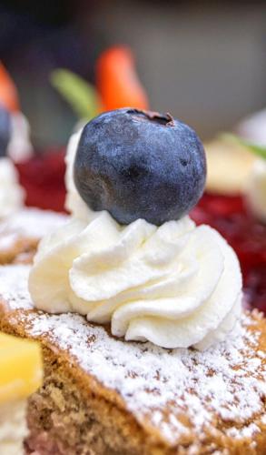 a piece of cake with a blueberry on top of it at Fürstenhof Landgasthaus & Hotel in Erfurt