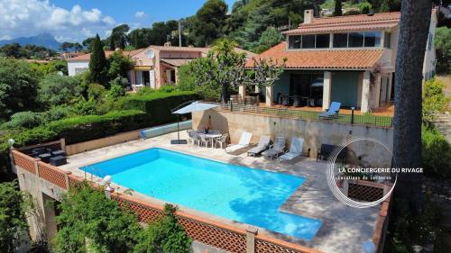 une image d'une piscine en face d'une maison dans l'établissement Villa Le Sud - Piscine - Vue dégagée et aperçu mer, à Carqueiranne