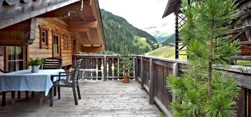 a wooden deck with a table and chairs on a house at Oberschupferhof in Außervillgraten