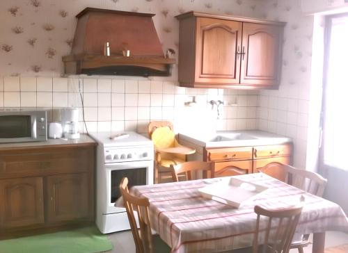 a kitchen with a table and a kitchen with a stove and cabinets at Maison enchanteur à Berrwiller avec jardin paisible in Berrwiller