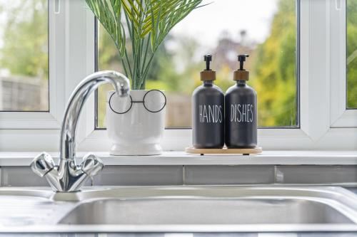zwei Flaschen auf einer Küchenspüle neben einem Fenster in der Unterkunft Luxury Birmingham Solihull Spacious Home - Driveway - Groups of 8 Max - 3 Bedrooms 4 or 6 Beds Fully Equipped Home - Near City Centre NEC HS2 Sites Edgbaston Moseley& lots more! in Birmingham
