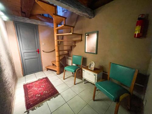 a living room with two chairs and a spiral staircase at La Maison Bleue - Historic House in the Heart of Riquewihr in Riquewihr
