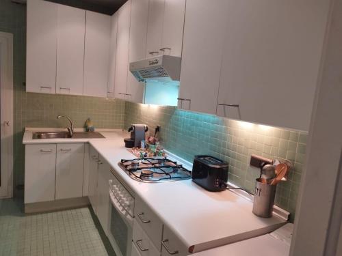 a kitchen with white cabinets and a stove top oven at Apartamento supercéntrico "Tarraco Arena" con ascensor y parking incluído in Tarragona