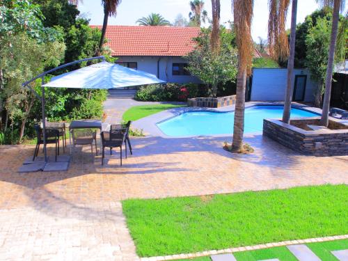 patio con tavolo e ombrellone accanto alla piscina di Nouvelle Ere Beauty Spa & Boutique Guesthouse a Centurion