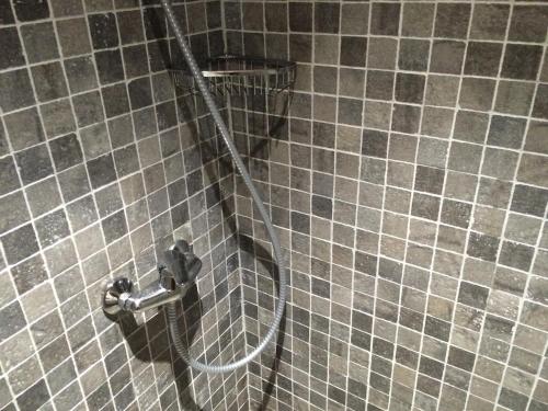 une douche avec un tuyau sur un mur carrelé dans l'établissement I Caselli, mini villa Vue Mer dans résidence calme et arborée, à Lecci