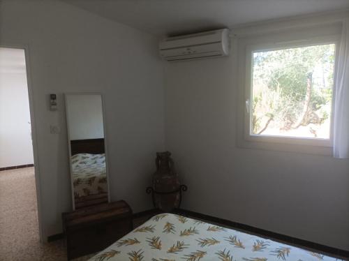 une chambre avec un lit, une fenêtre et un miroir dans l'établissement I Caselli, mini villa Vue Mer dans résidence calme et arborée, à Lecci