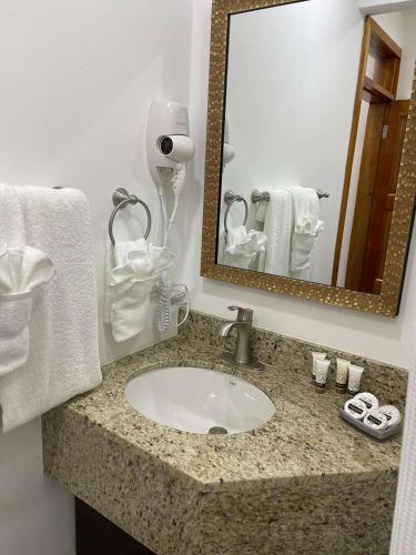 a bathroom with a sink and a mirror and towels at Best Western Grand Baymen Gardens in San Pedro