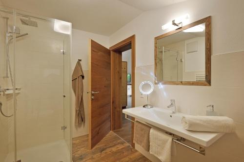 ein Bad mit einem Waschbecken, einer Dusche und einem Spiegel in der Unterkunft Ferienwohnung Sonnblick in Ramsau im Zillertal