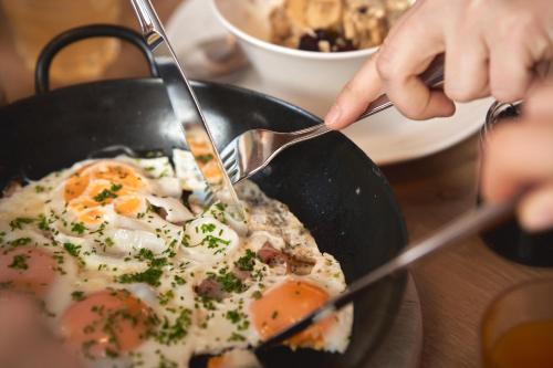 a person is eating food in a frying pan at Pension Vier Jahreszeiten in Saalbach Hinterglemm