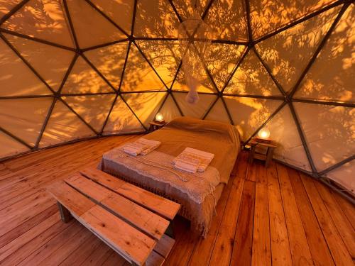 a room with a bed and a bench in a yurt at La Templanza EcoGlamping in Rincón de los Oliveras
