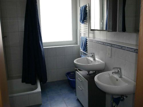 ein Badezimmer mit zwei Waschbecken, einer Badewanne und einem Spiegel in der Unterkunft Ferienhof Hirschfeld in Pfalzgrafenweiler