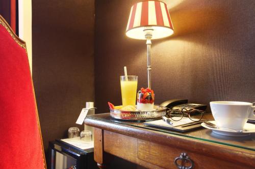 a table with a lamp and a drink on it at Hotel Trianon Rive Gauche in Paris
