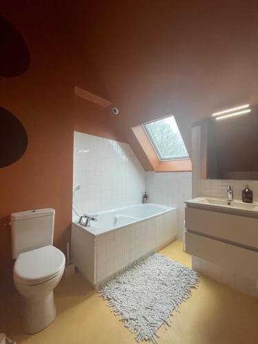 a bathroom with a tub and a toilet and a sink at La Lisiere Du Bois in Saint-Senier-de-Beuvron