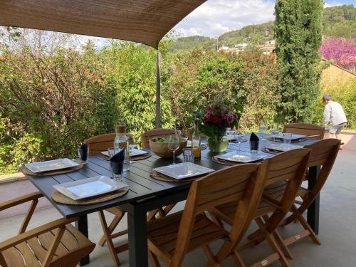 une table en bois entourée de chaises sur la terrasse. dans l'établissement Var Draguignan Vacation Rental, à Draguignan