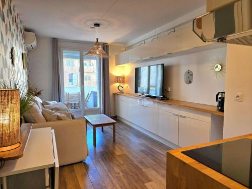 une cuisine avec des armoires blanches et un salon dans l'établissement Les Lavandes - à 5min de la mer à pieds , avec balcon et parking - BY AURAconciergerie, aux Lecques