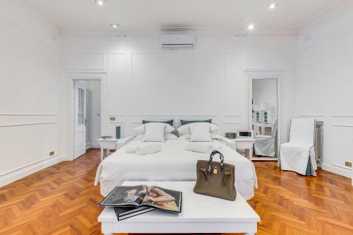 una camera bianca con un letto e un tavolo con una borsa di New opening Spagna Suite a Roma