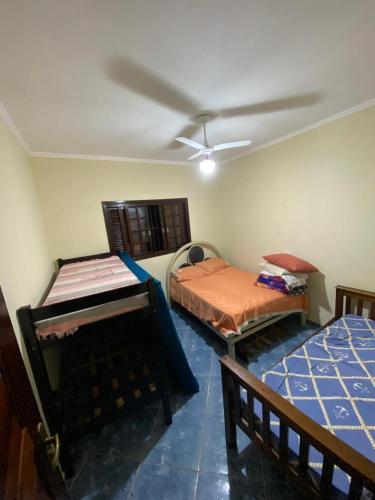 a room with two beds and a ceiling fan at Casa na Praia Bertioga in Bertioga