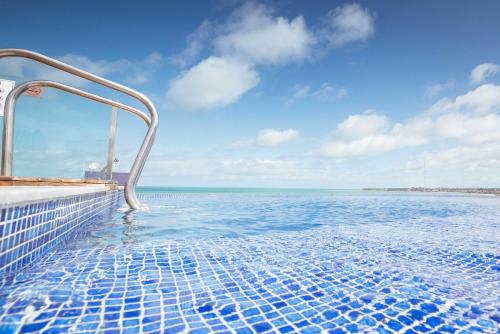 a swimming pool with a view of the ocean at Apto c otima localizacao a 120m da praia de Tambau in Tambaú