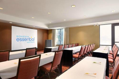 a conference room with tables and chairs and a screen at Sonesta Essential Junction City in Junction City