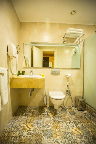 a bathroom with a toilet and a sink and a mirror at Colosseum Marina Hotel in Batumi