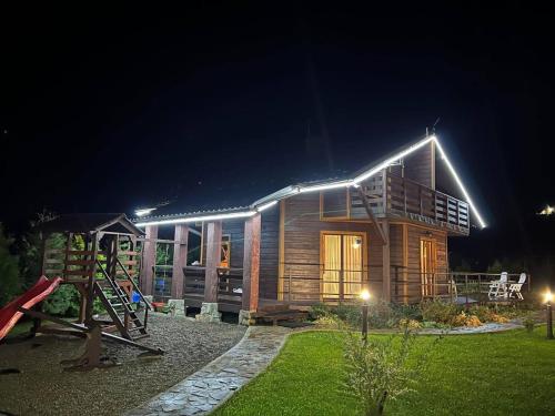 una casa de madera con luces encendidas por la noche en Котедж “Гуркало", en Korchin