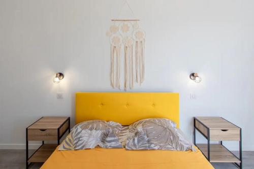 - une chambre avec un lit jaune et 2 tables de chevet dans l'établissement l'échappée belle - vineyard-jacuzzi and BBQ, à Nice