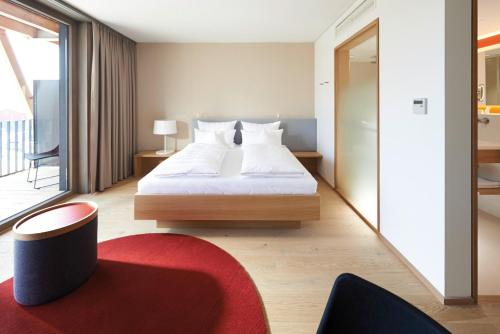 a bedroom with a large bed and a red rug at Hotel Bora HotSpaResort in Radolfzell am Bodensee
